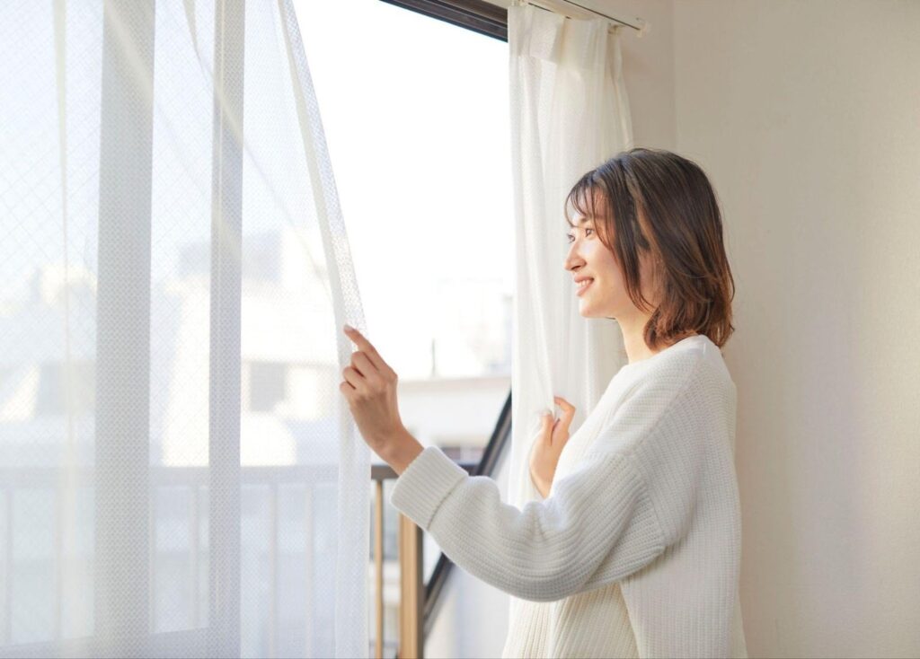 カーテンをあける女性